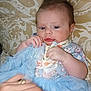 Summer is registered to the contest to win money with this photo: baby, infant, blue_skirt, floral_outfit, cushion, patterned_background, hand, ring, nail_polish, soft_cloth, portrait, indoor, child, cute, lying_down, fabric, person, skin, face, eyelashes
