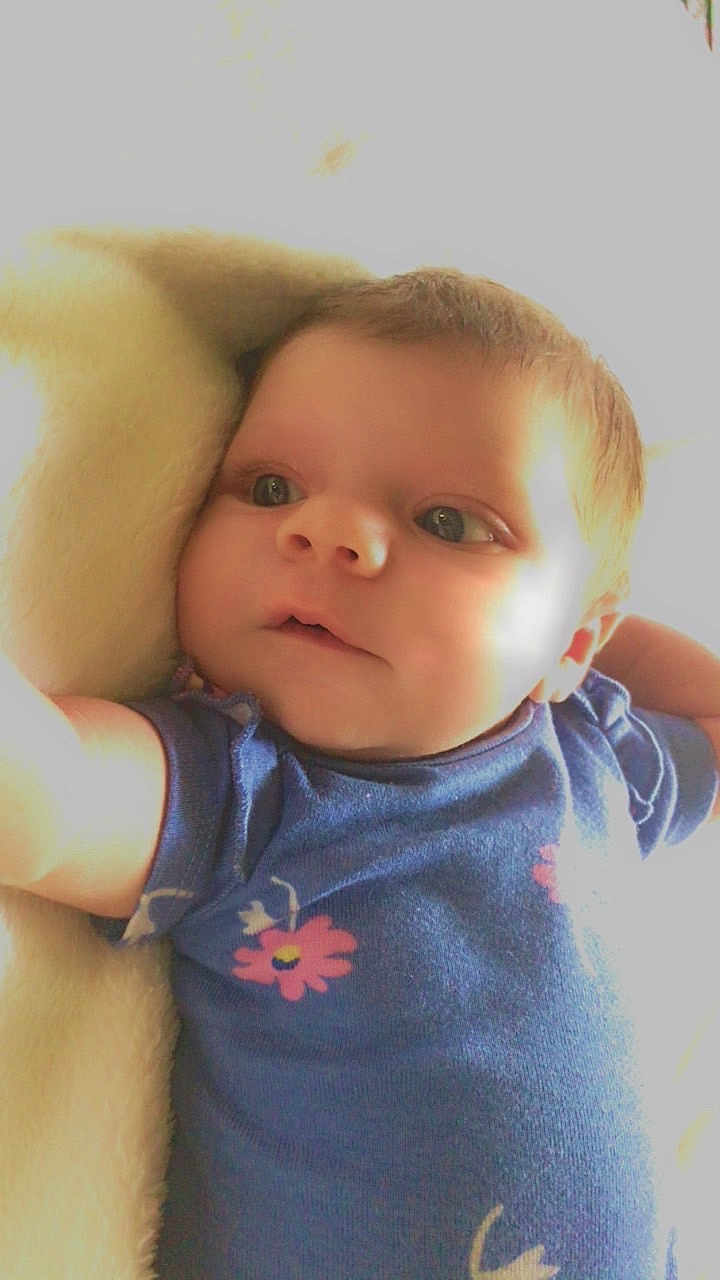 Willow joined the competition — help win amazing prizes! baby, infant, blue_onesie, flower_pattern, soft_blanket, cute, portrait, child, young, skin, face, eyes, arm, hand, lying_down, indoor, closeup, expression, adorable, newborn