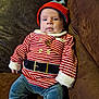 Arley joined the competition — help win amazing prizes! baby, blue_pants, brown_couch, casual, child, comfortable, couch, cozy, cute, face, festive_clothing, indoors, infant, portrait, red_booties, red_hat, seated, soft_lighting, striped_shirt, young_child