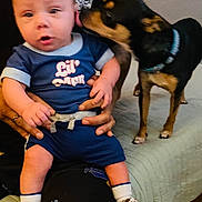 Victor joined the competition — help win amazing prizes! baby, infant, child, dog, puppy, animal, kiss, tongue, onesie, blue_clothing, socks, hands, person, lap, bed, blanket, indoor, candid, blur, pet_interaction