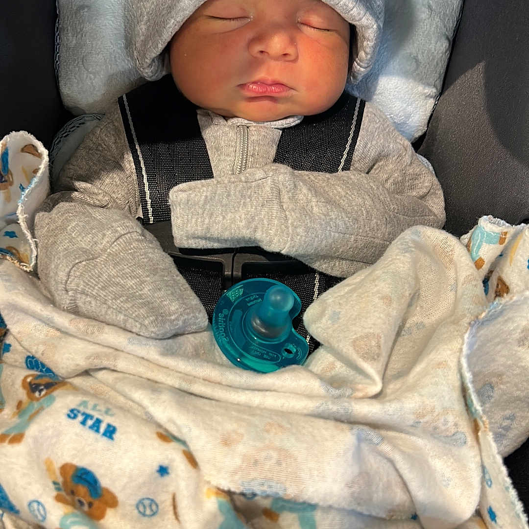 Arley is registered to the contest to win money with this photo: newborn, baby, sleeping, infant, hat, gray_hat, pacifier, blanket, swaddled, car_seat, portrait, cozy, clothing, mittens, face, closed_eyes, indoors, photography, soft_blanket, resting