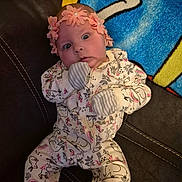 Miracle is registered to the contest to win money with this photo: baby, infant, face, headband, pajamas, animal_print, couch, blanket, expression, wide_eyes, hand, gloves, indoor, fabric, comfort, person, child, cute, soft_toys, colorful