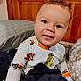 Jameson is registered to the contest to win money with this photo: toddler, child, baby, curly_hair, pajamas, dinosaur_print, pumpkin_print, blanket, bed, pillow, wooden_headboard, indoor, smiling, face, eyes, cute, cozy, person, portrait, comfortable