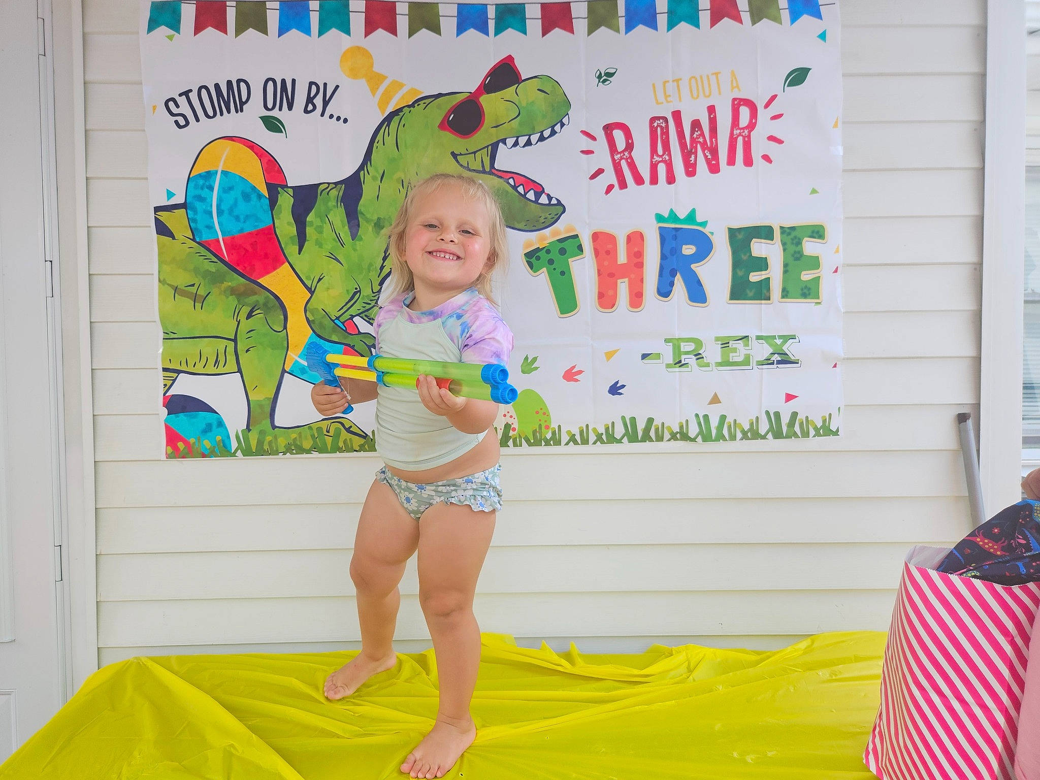 Corinne is registered to the contest to win money with this photo: advertising, banner, barefoot, child, competition, event, flag, fun, green, happy, human_leg, joy, leisure, person, room, sandal, shorts, smile, t_shirt, thigh