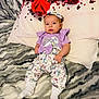 Génesis is registered to the contest to win money with this photo: baby, infant, unicorn, clothing, purple, white_socks, pillow, red_roses, blanket, patterned_blanket, headband, cute, lying_down, indoor, soft_texture, cozy, young_child, person, resting, portrait