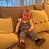 baby, child, infant, couch, pillow, curtain, window, indoors, clothing, footwear, person, seated, cute, home, soft_lighting, face, hair, expression, cozy, relaxing