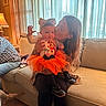 Kylie is registered to the contest to win money with this photo: baby, child, woman, couch, indoor, curtains, lamp, orange_tutu, bow, smiling, kiss, affection, home, furniture, dog_tail, cozy, person, clothing, sitting, warm_lighting