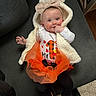 Kylie is registered to the contest to win money with this photo: baby, infant, tutu, headband, bow, vest, couch, clothing, person, child, indoor, toddler, cute, fashion, orange, white, black, smile, face, hand