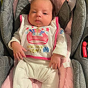 Jade a rejoint le concours — aidez-le/la à gagner de superbes lots ! baby, car_seat, child, clothing, comfort, cushion, cute, fabric, face, fingers, hand, indoor, infant, newborn, person, pink_bib, portrait, resting, seatbelt, white_outfit