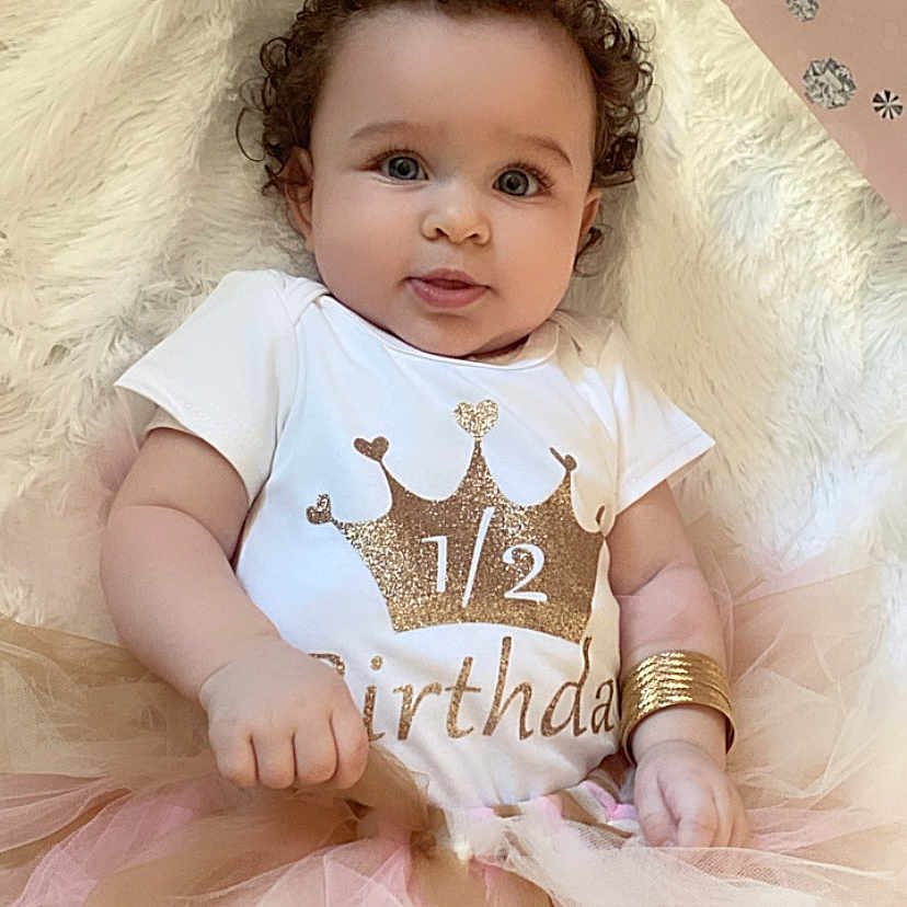 Maelee joined the competition — help win amazing prizes! accessories, baby, bodypart, clothing, costume, crown, dress, face, finger, hand, hat, head, jewelry, necklace, person, photography, portrait, sitting, t_shirt, tiara