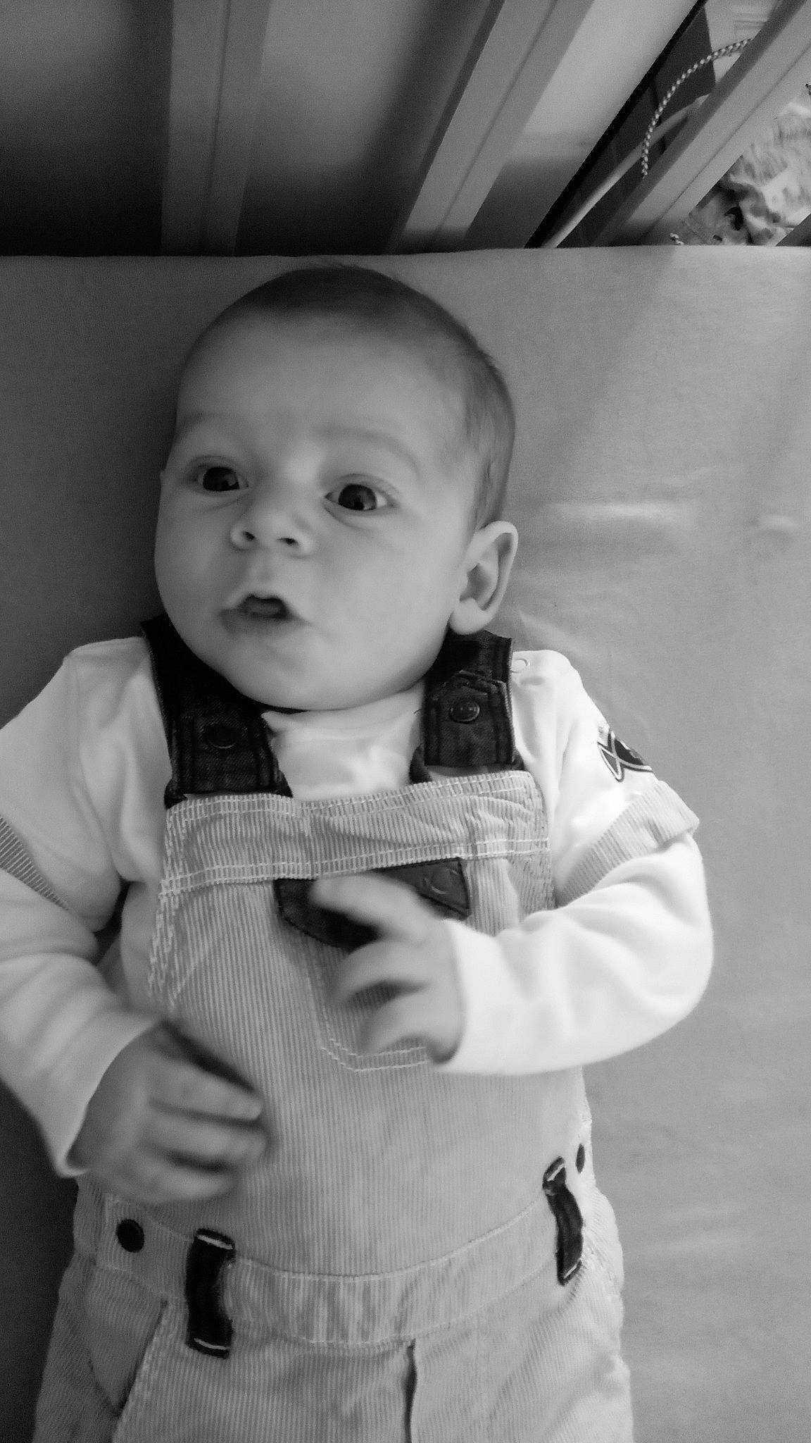 élye participe au concours pour gagner de l'argent avec cette photo : arm, baby, baby_toddler_clothing, black, black_and_white, cheek, eye, flash_photography, gesture, hand, happy, iris, mouth, nose, outerwear, person, skin, sleeve, smile, standing