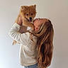 Blue participe au concours pour gagner de l'argent avec cette photo : puppy, dog, woman, person, cuddle, kiss, pet, fluffy, brown_fur, tongue_out, smiling, glasses, long_hair, white_sweater, jeans, indoor, portrait, standing, wall, adorable