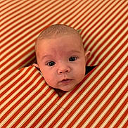 Ezio participe au concours pour gagner de l'argent avec cette photo : baby, child, closeup, curious, cute, expression, eyes, face, head, hole, indoor, infant, orange, pattern, peek, portrait, soft_light, striped_fabric, white, young