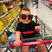 Louis is registered to the contest to win money with this photo: adult, aisle, child, clothing, floor, footwear, grocery, hat, person, plastic_bottle, product, retail, shelf, shopping, shopping_cart, store, sunglasses, supermarket, toddler, toy