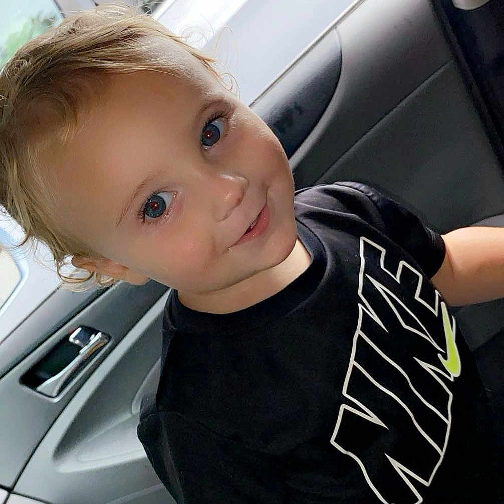 Jaxtyn is registered to the contest to win money with this photo: accessories, baby, belt, bodypart, car, clothing, face, hair, happy, head, mouth, person, photography, portrait, shirt, sleeve, smile, t_shirt, transportation, vehicle
