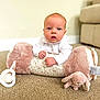baby, infant, child, carpet, plush_pillow, soft_toy, floor, indoor, blue_eyes, white_clothing, curious_expression, hands, couch, blurred_background, home, cozy, face, portrait, cute, toddler