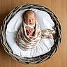 Caissian is registered to the contest to win money with this photo: newborn, baby, sleeping, infant, portrait, basket, blanket, swaddled, wooden_floor, indoor, top_down, peaceful, cozy, white_bedding, woven, round_basket, tiny_hands, closed_eyes, photography, family_photo