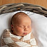 baby, newborn, sleeping, portrait, face, basket, blanket, swaddled, cozy, indoor, soft_lighting, peaceful, infant, head, closed_eyes, brown_hair, white_bedding, wooden_background, nursery, photography