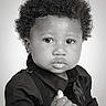 Azari is registered to the contest to win money with this photo: baby, child, portrait, black_and_white, curly_hair, serious_expression, face, eyes, lips, infant, fashion, dark_clothing, formalwear, sitting, studio, closeup, photography, monochrome, thumb, indoor