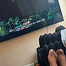 Azari is registered to the contest to win money with this photo: toddler, child, toys, carpet, living_room, television, subtitles, feet, furniture, black_chair, smile, person, indoors, playtime, curly_hair, colorful, relaxation, home, family, comfort