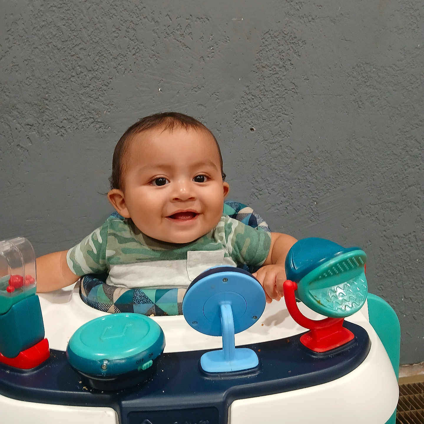 Jonah Gutierrez joined the competition — help win amazing prizes! baby, background, child, clothing, cute, face, floor, furniture, happy, head, indoor, infant, person, plastic, playtime, seat, sitting, smiling, toy, walker