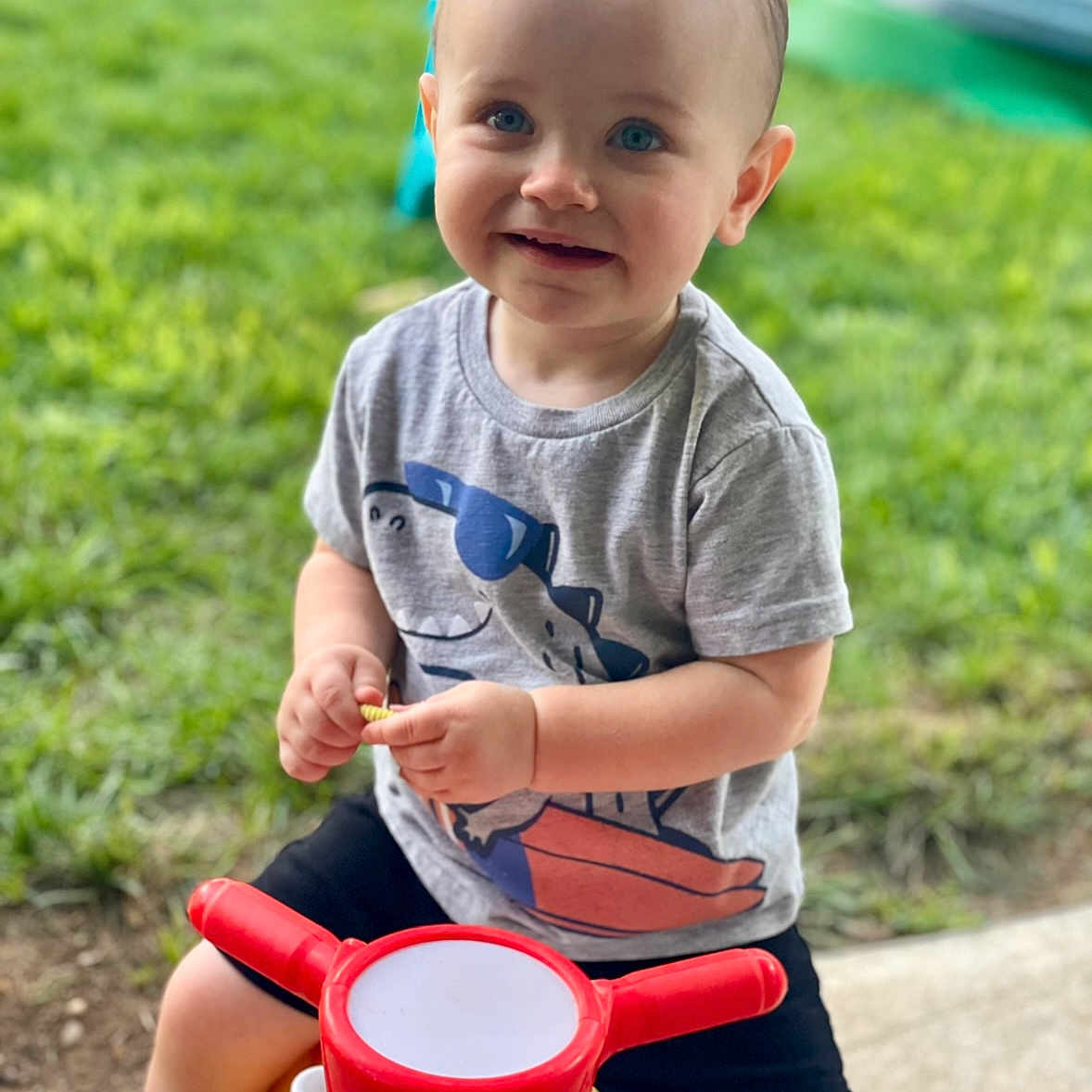 Jaxon is registered to the contest to win money with this photo: ball, boy, child, clothing, cup, face, football, grass, head, male, person, photography, plant, portrait, shorts, sitting, soccer, soccerball, sport, t_shirt