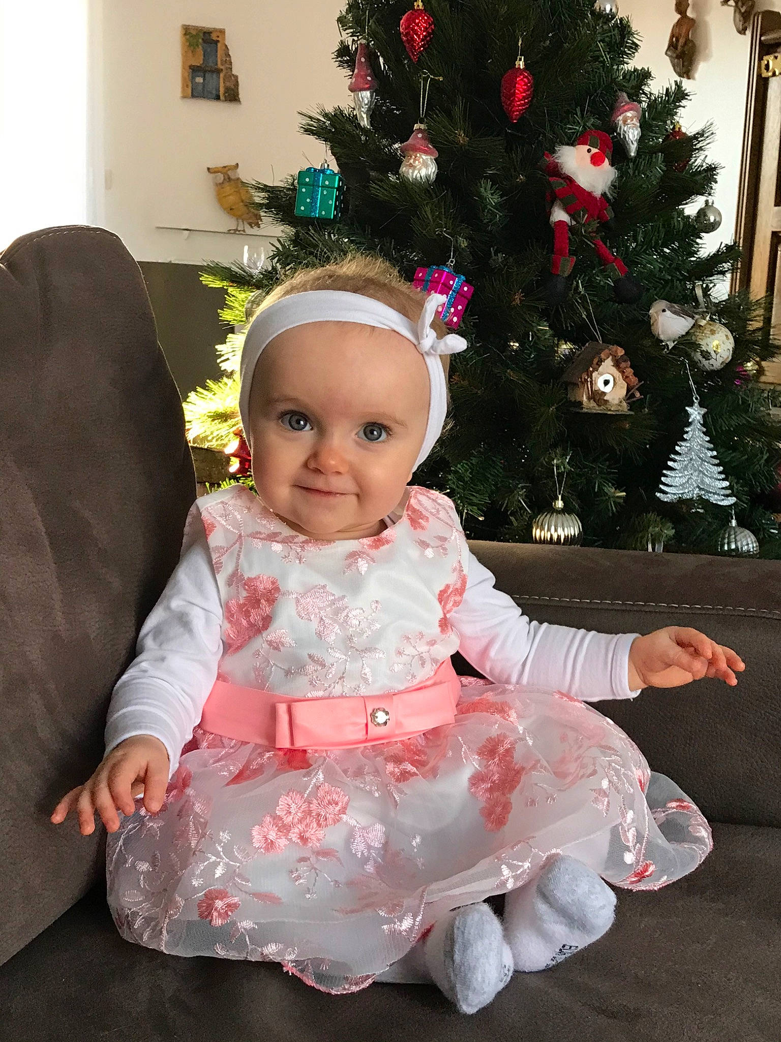 Raphaëlle a rejoint le concours — aidez-le/la à gagner de superbes lots ! baby, child, christmas, christmas_decoration, christmas_eve, christmas_ornament, christmas_tree, dress, head, holiday, interior_design, joy, person, pink, plant, room, sitting, smile, toddler, tree