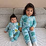 child, baby, toddler, siblings, pajamas, matching_clothes, blue, dinosaur_print, couch, sofa, smiling, sitting, indoor, home, cute, family, portrait, cozy, white_socks, curly_hair