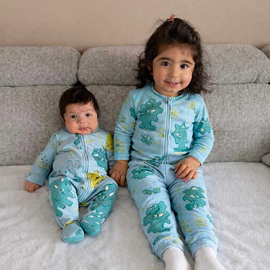 Izak participe au concours pour gagner de l'argent avec cette photo : child, baby, toddler, siblings, pajamas, matching_clothes, blue, dinosaur_print, couch, sofa, smiling, sitting, indoor, home, cute, family, portrait, cozy, white_socks, curly_hair