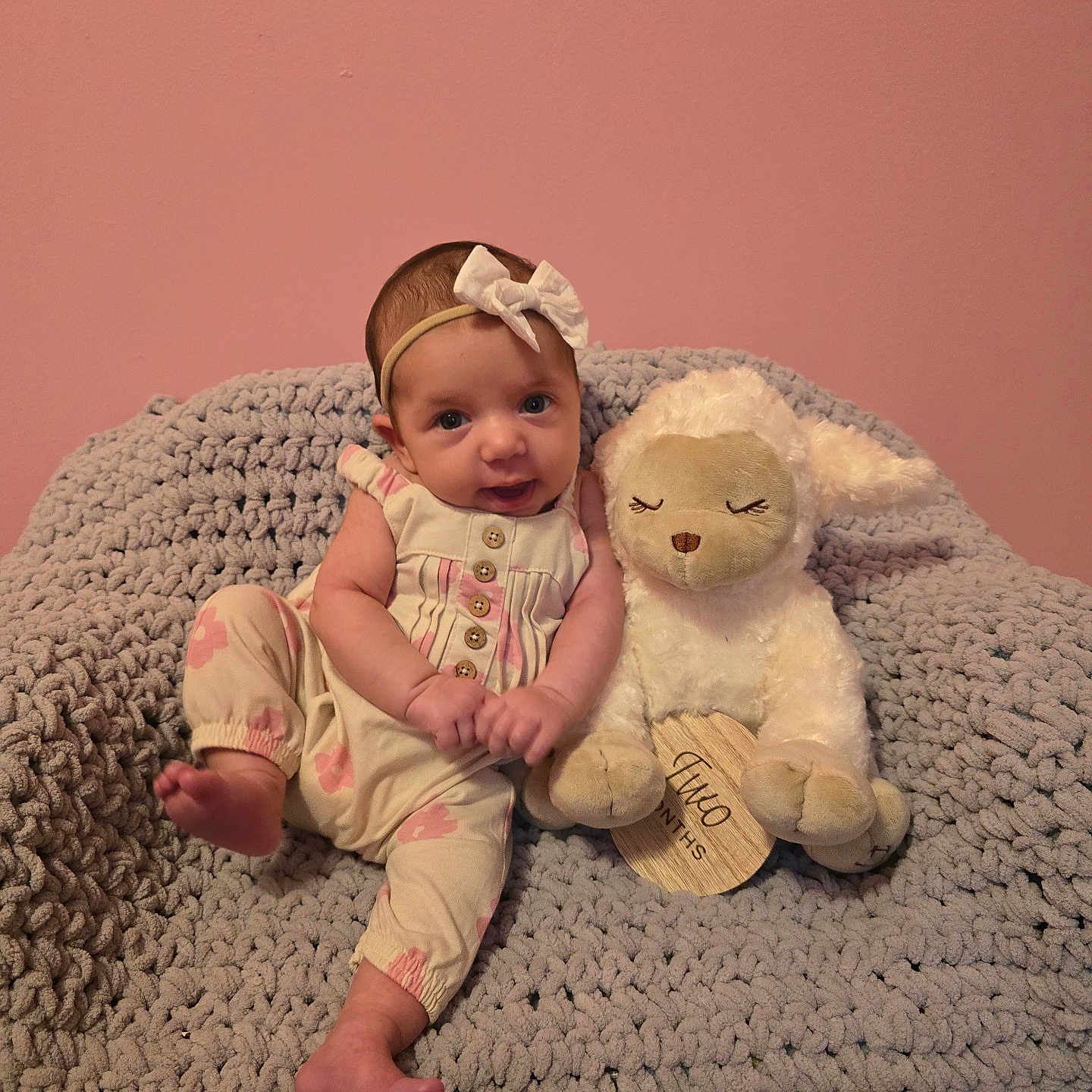 Harper joined the competition — help win amazing prizes! baby, blanket, bow, child, clothing, cozy, cute, headband, indoor, infant, knit, lamb, milestone, pink_wall, plush_toy, portrait, sitting, smiling, stuffed_animal, two_months