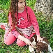 Lorine participe au concours pour gagner de l'argent avec cette photo : child, girl, puppy, dog, grass, tree, stick, braids, pink_clothing, outdoor, playful, pet, animal, nature, young, sitting, cute, summer, casual, fun