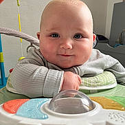 Harrison is registered to the contest to win money with this photo: baby, infant, face, chubby_cheeks, toy, indoor, close_up, curious, child, cute, playtime, colorful, smiling, clothing, person, young, soft_light, head, hands, background