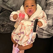 Arisa is registered to the contest to win money with this photo: baby, infant, pacifier, bottle, robe, slippers, remote_control, blanket, indoor, couch, child, cute, soft, relaxed, person, home, cozy, sleepwear, fuzzy, comfort