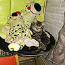 cat, kitten, tabby, sleeping, stuffed_animals, plush_toys, dog_toys, chair, green_chair, indoor, living_room, brick_wall, furniture, cushion, seated, relaxed, pet, whiskers, striped_fur, flash_photography
