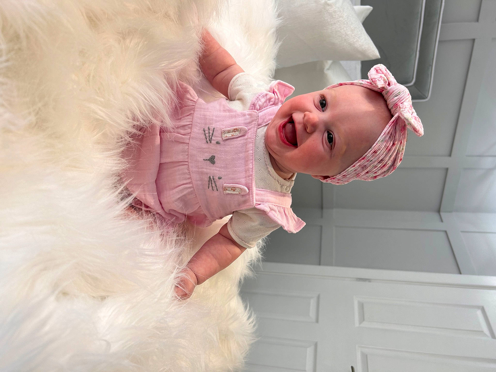 Indie is registered to the contest to win money with this photo: arm, baby, baby_toddler_clothing, child, comfort, dress, fun, fur, happy, headgear, joy, linens, magenta, person, pink, portrait_photography, room, skin, sleeve, smile
