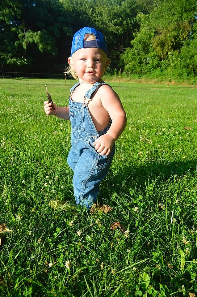Ares is registered to the contest to win money with this photo: baby, baby_toddler_clothing, baseball_cap, cap, grass, grass_family, grassland, groundcover, happy, hat, headwear, lawn, meadow, natural_environment, people_in_nature, person, plant, prairie, smile, sunlight
