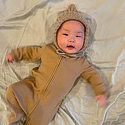 Rocky joined the competition — help win amazing prizes! baby, infant, onesie, knitted_hood, blanket, lying_down, cute, smiling, child, portrait, indoors, soft_lighting, warm_colors, cozy, person, young_child, sleepwear, baby_clothes, happy, face