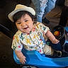 Kross is registered to the contest to win money with this photo: toddler, child, hat, toy_car, indoor, smiling, shirt, cactus_pattern, blue, footwear, person, jeans, ripped_jeans, car_toy, steering_wheel, floor, furniture, happy, cute, play