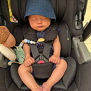 Elijah joined the competition — help win amazing prizes! baby, infant, sleeping, car_seat, hat, blue_hat, black_car_seat, toy, stuffed_animal, safety_harness, child, cute, peaceful, hands, feet, indoors, portrait, seat_belt, comfort, resting