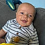 Elijah joined the competition — help win amazing prizes! baby, smiling, striped_shirt, polo_shirt, couch, gray_couch, toy, colorful_toy, controller, game_controller, blue_controller, indoors, child, happy, face, head, arm, button, fabric, relaxing