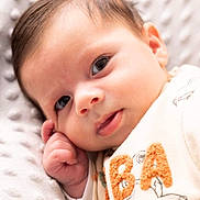 Lilian participe au concours pour gagner de l'argent avec cette photo : baby, infant, close_up, face, hand, eyes, blanket, soft_texture, clothing, embroidered_letters, dog_illustration, cute, resting, portrait, newborn, skin, young_child, indoors, warm, comfort