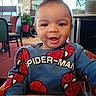 toddler, child, smiling, sweater, spider_man, indoor, restaurant, table, chair, plant, happy, face, person, casual_clothing, cute, portrait, seated, young_child, bright, daylight
