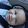 baby, smile, car_seat, child, blue_clothing, infant, face, seatbelt, warning_label, happy, young_child, safety, portrait, cute, indoors, person, head, closeup, cozy, drool