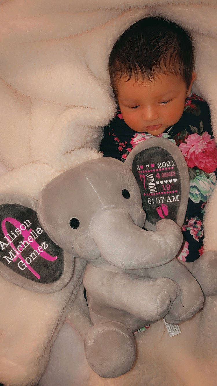 Allison is registered to the contest to win money with this photo: arm, baby, baby_toddler_clothing, cheek, doll, eyelash, finger, fur, human_body, mammal, neck, nose, person, pink, plush, skin, sleeve, stuffed_toy, textile, toddler