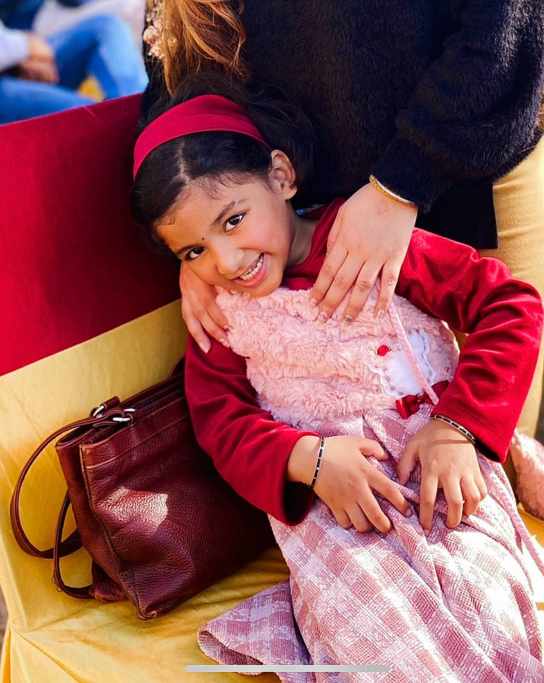 Seerat is registered to the contest to win money with this photo: child, comfort, event, finger, fun, gesture, happy, joy, lap, leisure, magenta, pattern, person, pink, purple, sitting, skin, smile, textile, thigh