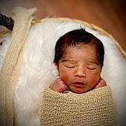 Ezra is registered to the contest to win money with this photo: newborn, baby, sleeping, wrapped, blanket, knitted, cushion, soft, face, head, peaceful, infant, closeup, portrait, indoors, cozy, warm, wooden_floor, resting, child