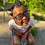 accessories, child, clothing, face, female, footwear, girl, glasses, grass, happy, head, person, photography, plant, portrait, shoe, shorts, sitting, smile, sunglasses