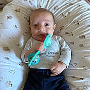 Ayden participe au concours pour gagner de l'argent avec cette photo : baby, infant, toy, pillow, sheep_pattern, clothing, grey_shirt, navy_pants, hand, face, expression, lying_down, cute, indoor, child, young_child, person, comfort, playful, soft