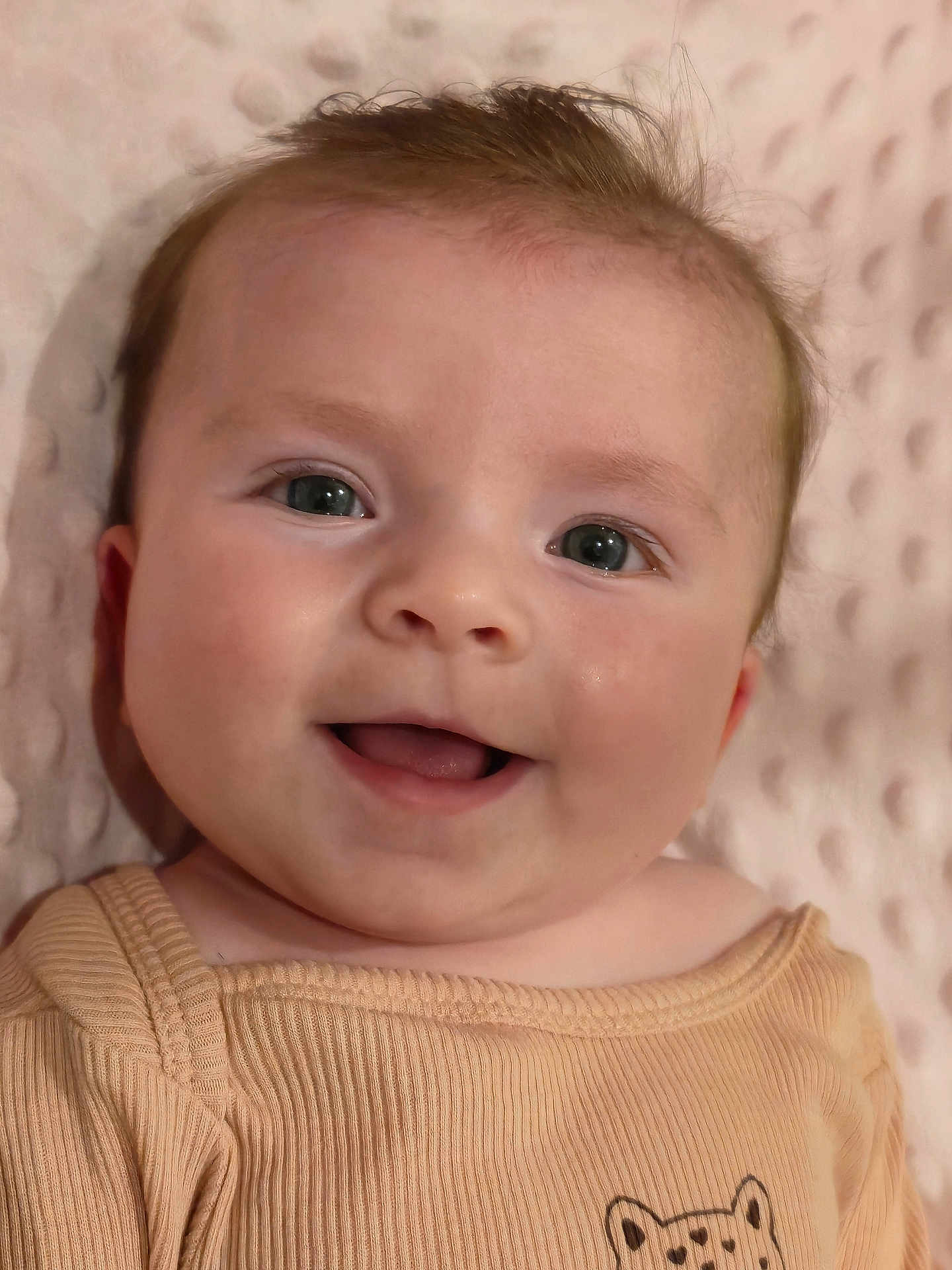 Zélie participe au concours pour gagner de l'argent avec cette photo : baby, infant, smile, face, eyes, cheeks, skin, portrait, cute, baby_clothes, onesie, blanket, lying_down, closeup, happy, young_child, eyelashes, tongue, head, hair