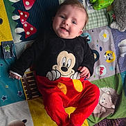 Zélie participe au concours pour gagner de l'argent avec cette photo : baby, infant, smiling, playmat, mickey_mouse_clothing, red_pants, plush_toy, toy_car, colorful, patterned_blanket, face, blue_eyes, hands, feet, lying_down, soft_toys, mushrooms, stars, hedgehog, cute